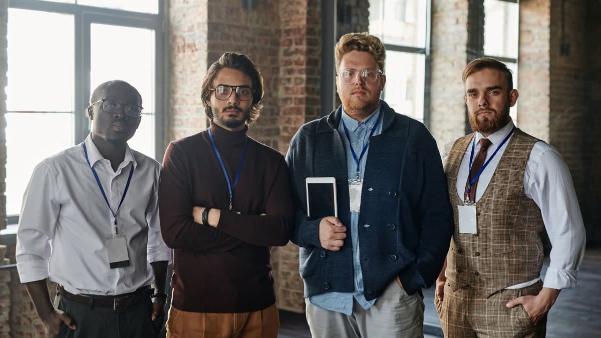 Portrait of a diverse group of four serious professionals standing indoors with tablets.