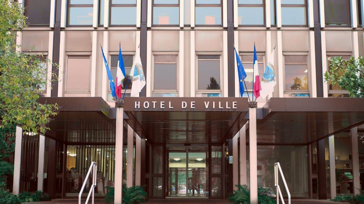 Front view of Hotel de Ville in Vélizy-Villacoublay, France with flags and modern architecture.
