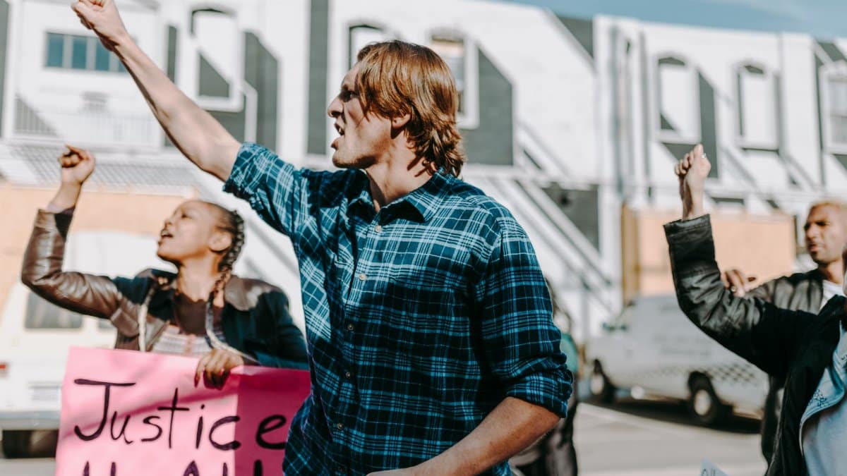 Group of diverse protesters holding signs and fists raised during a peaceful outdoor rally.