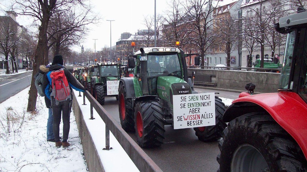 Farmers protest in urban street with tractors, highlighting their concerns in a snowy winter setting.