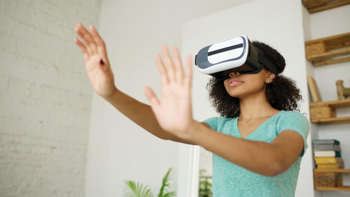Woman wearing VR headset engaging in virtual experience indoors.