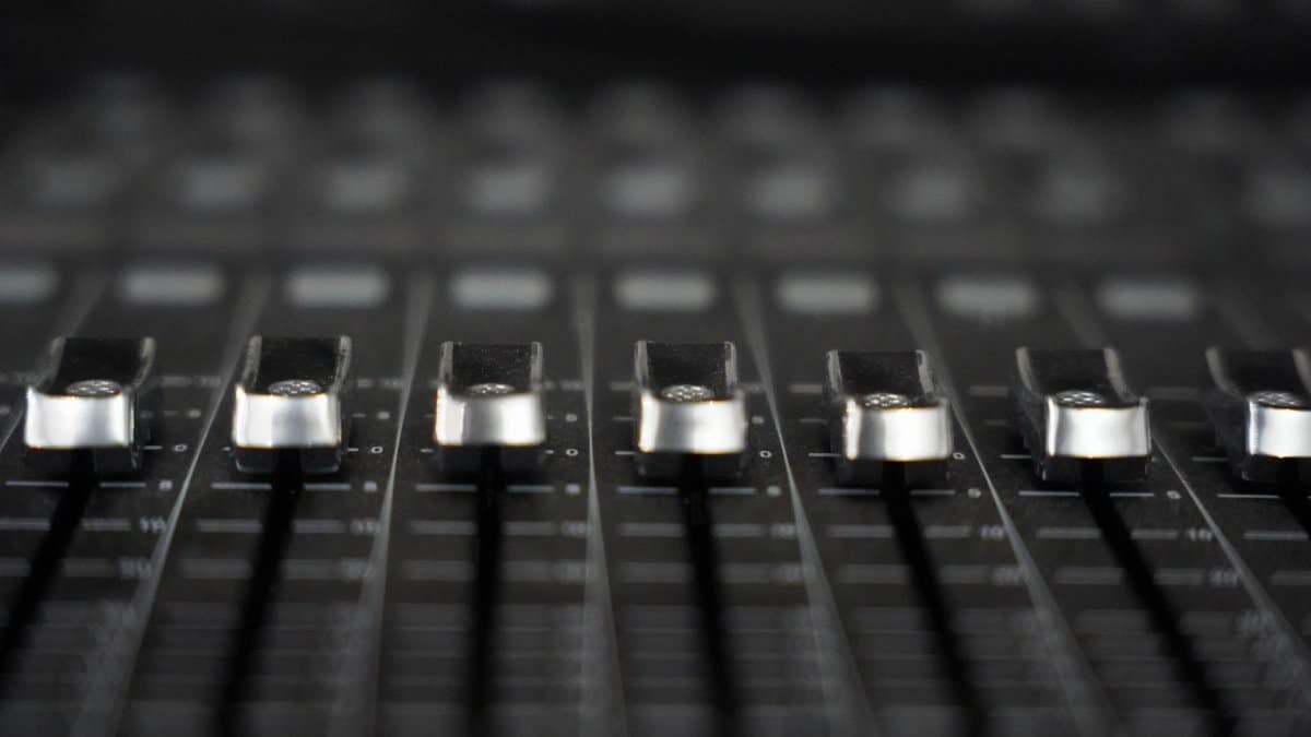 Detailed view of audio mixer faders, essential tool for sound engineering in studios.