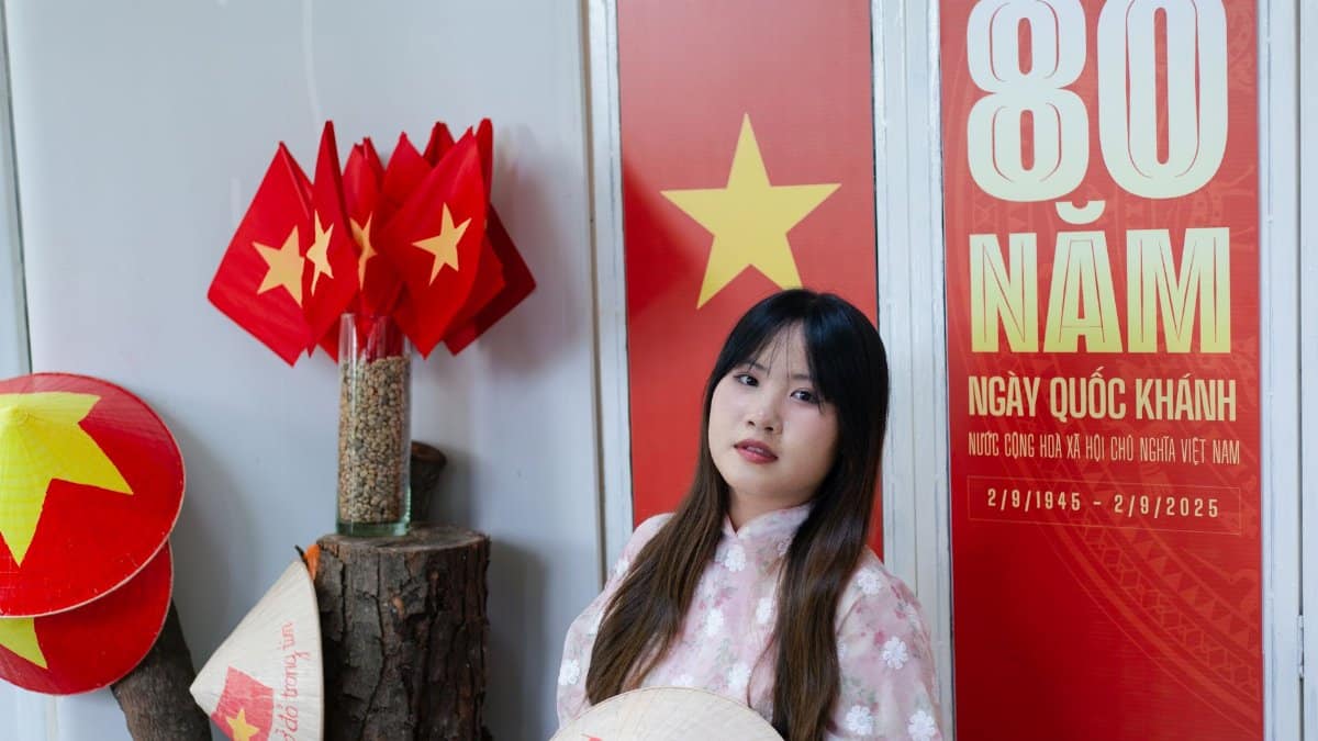 Portrait of a woman in traditional attire celebrating Vietnam National Day 80th anniversary with flags and decor.