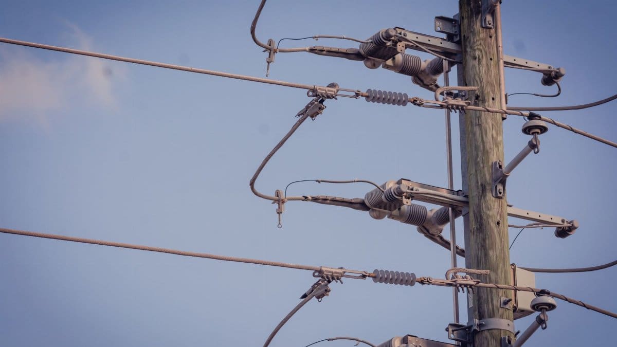Detailed view of a power pole and lines against a clear blue sky.