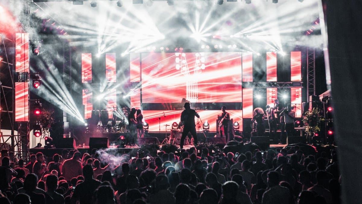 Energetic live music concert featuring performers on a vibrant stage, captivating a large audience.