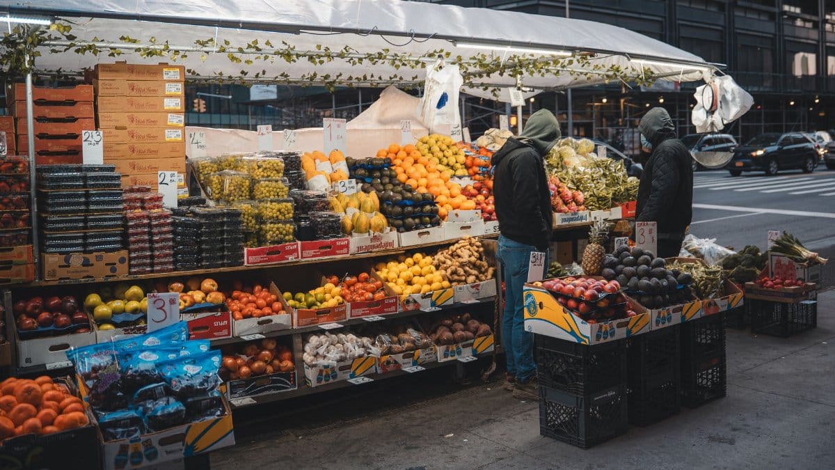Fresh fruits and vegetables at a bustling street market in New York City during daytime.