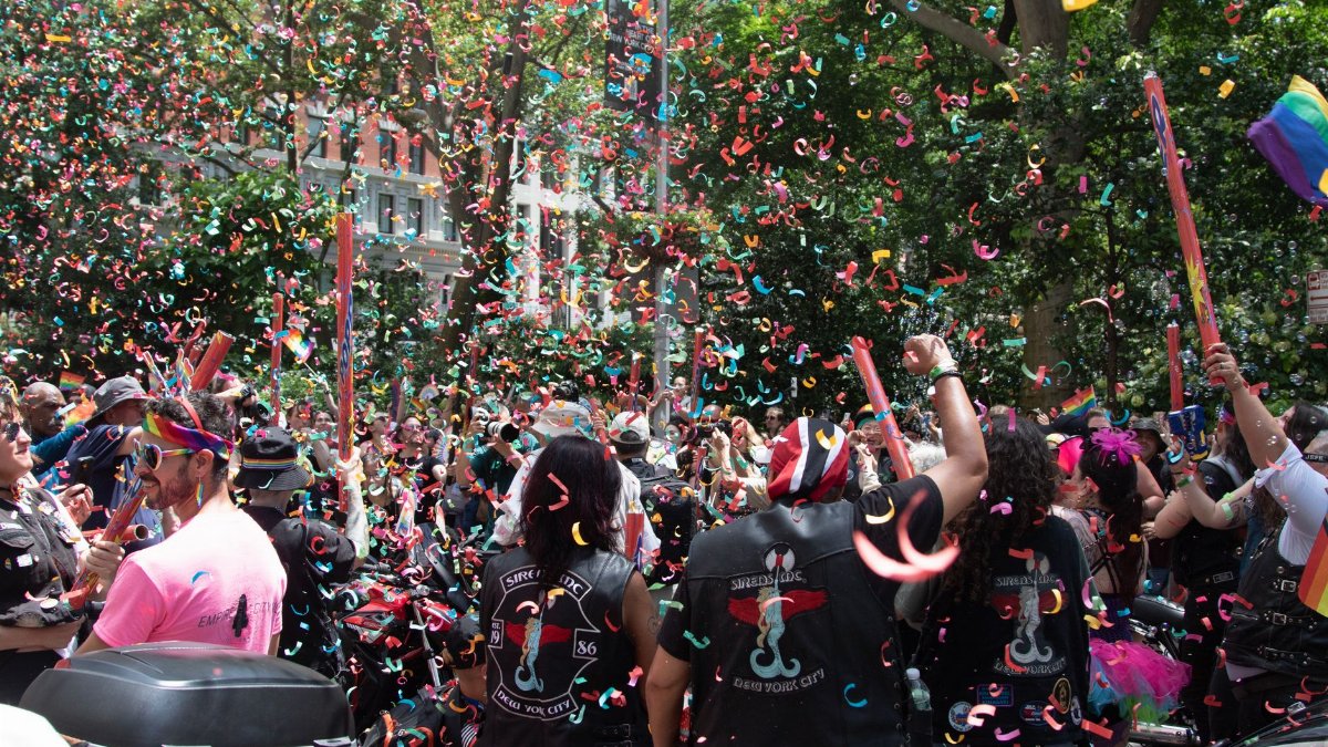 Exciting street parade in NYC with colorful confetti and diverse crowd celebrating pride.