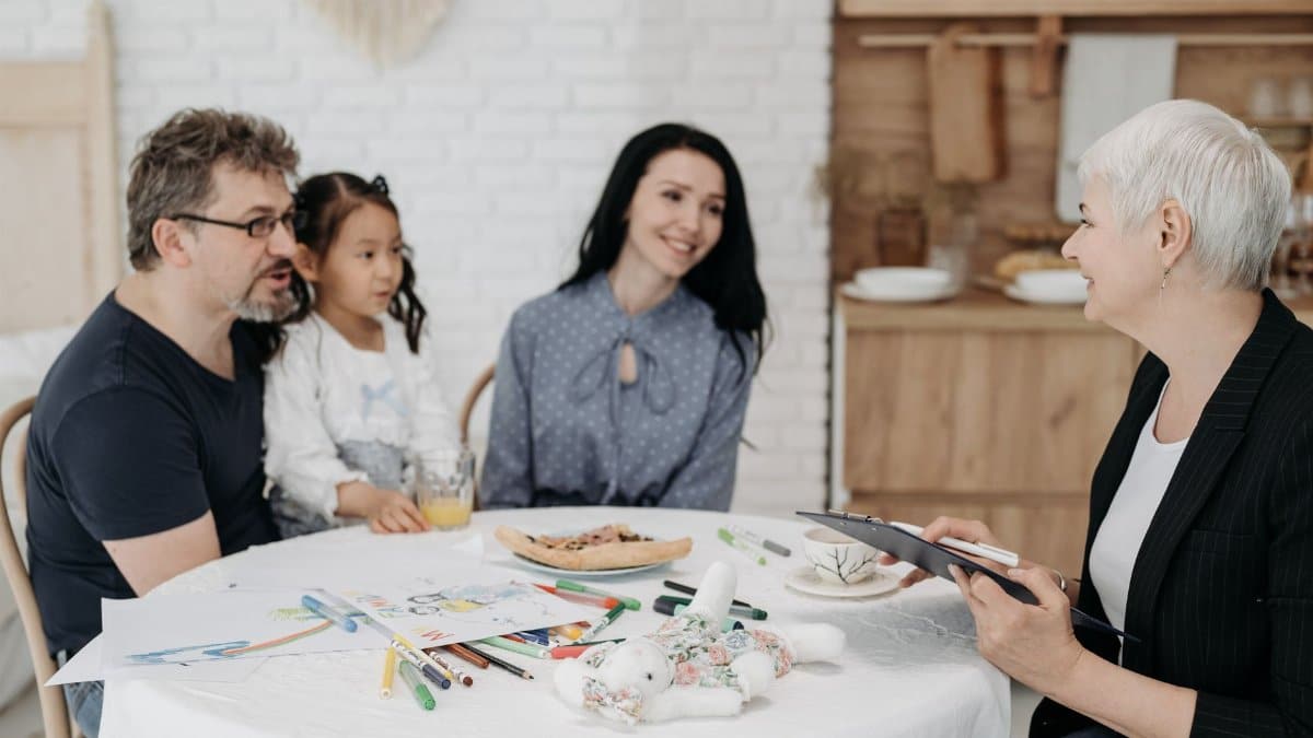 Adoptive family discussing with a social worker indoors, creating a warm, welcoming atmosphere.