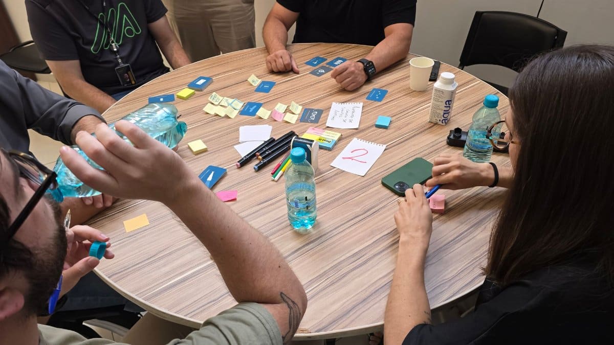 Group of adults collaborating at a round table with sticky notes and water bottles.