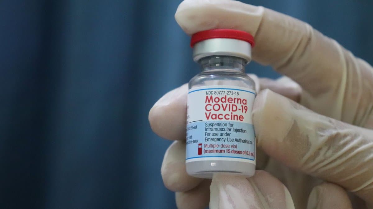 Close-up of gloved hand holding a Moderna COVID-19 vaccine vial, symbolizing immunization and protection.