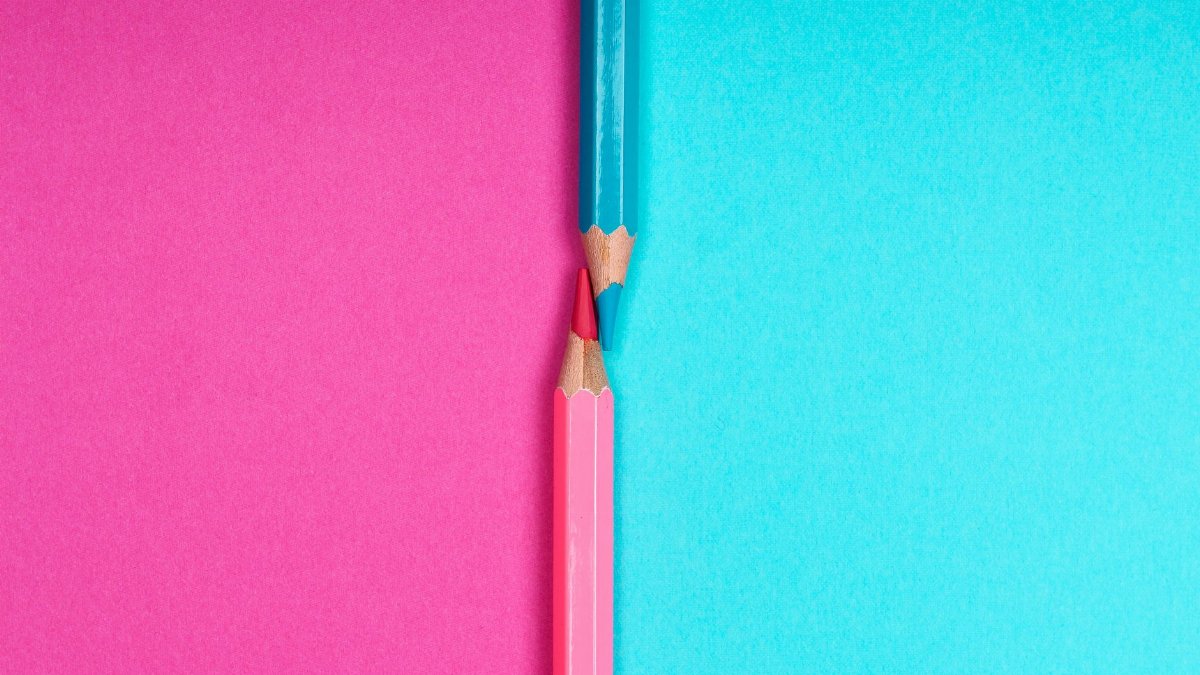 Close-up of sharpened colored pencils on a vibrant pink and blue background, showcasing creativity and contrast.
