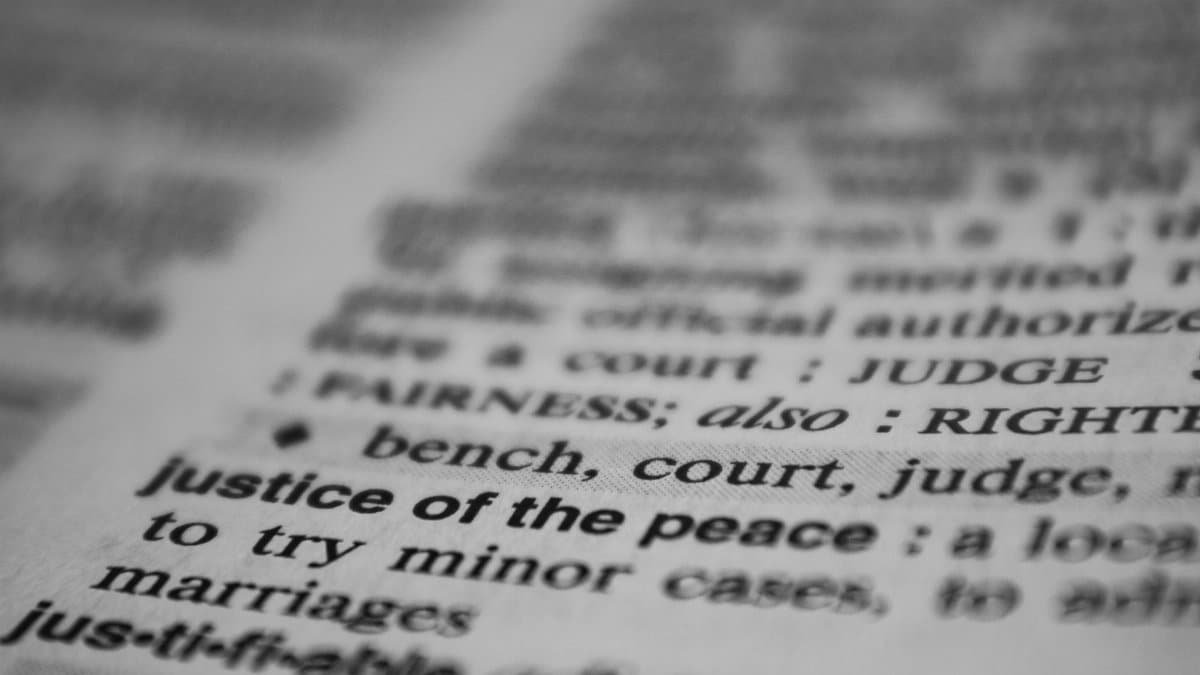 Selective focus on the word 'justice' in a dictionary, conveying law and fairness concepts.