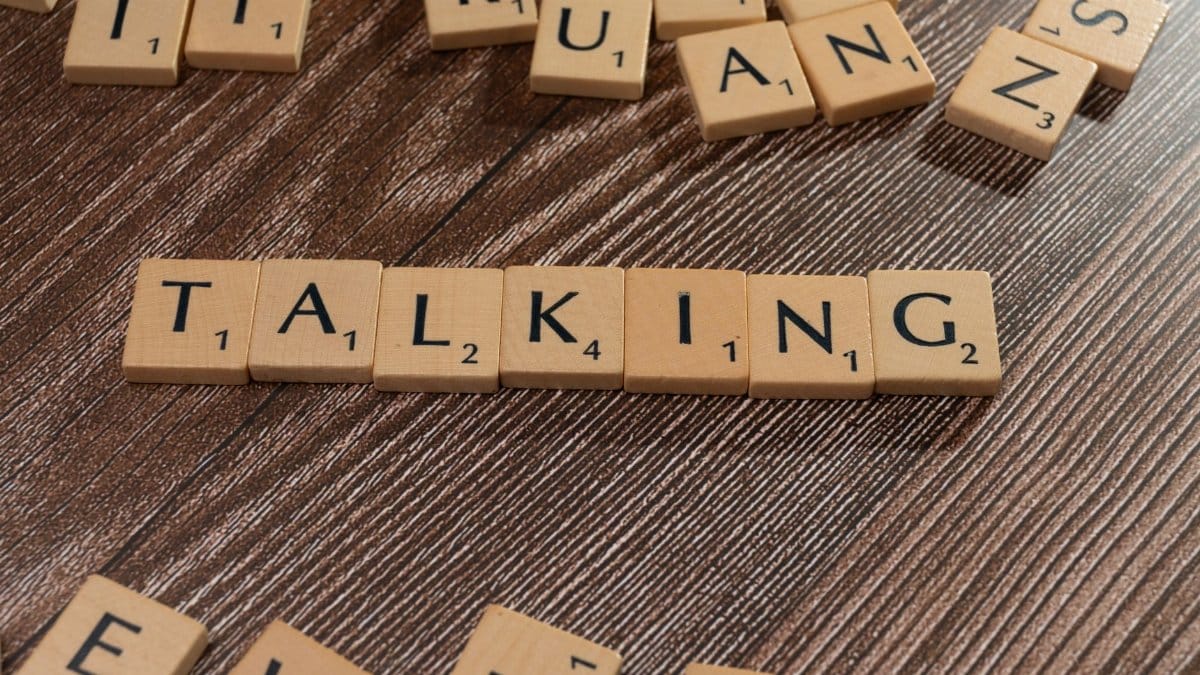 Scrabble tiles spelling 'Talking' on wooden surface, symbolizing communication.
