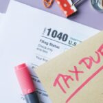 Close-up of IRS Form 1040 with 'Tax Due' note and stationery on a desk.