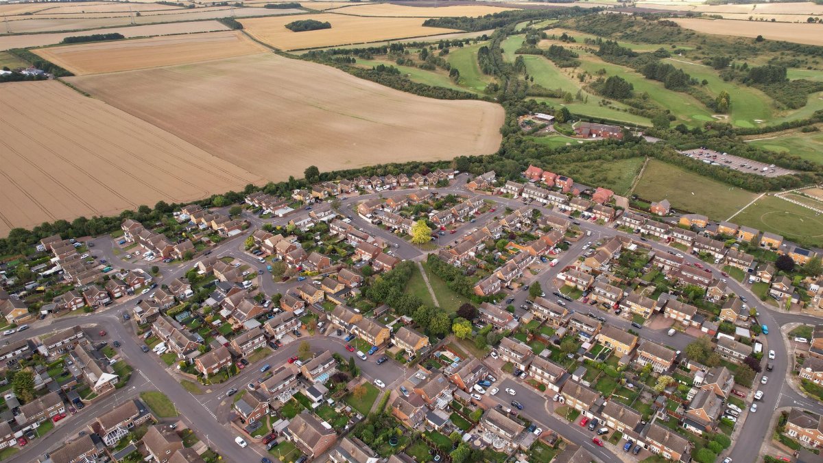Aerial landscape view of a residential area in Luton, showcasing roads, houses, and natural surroundings.
