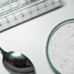 Metal spoon and white powder on a white countertop, suggesting substance use.