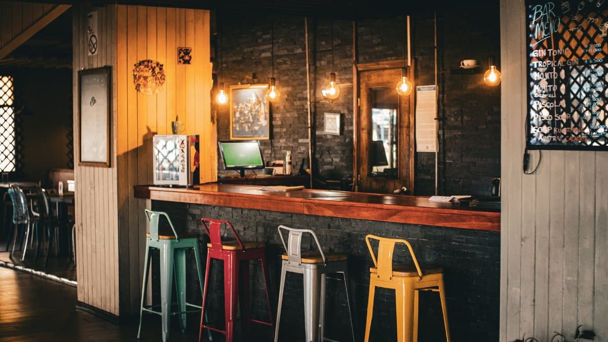 Warm and inviting rustic bar with colorful stools and ambient lighting, perfect for a relaxed evening.