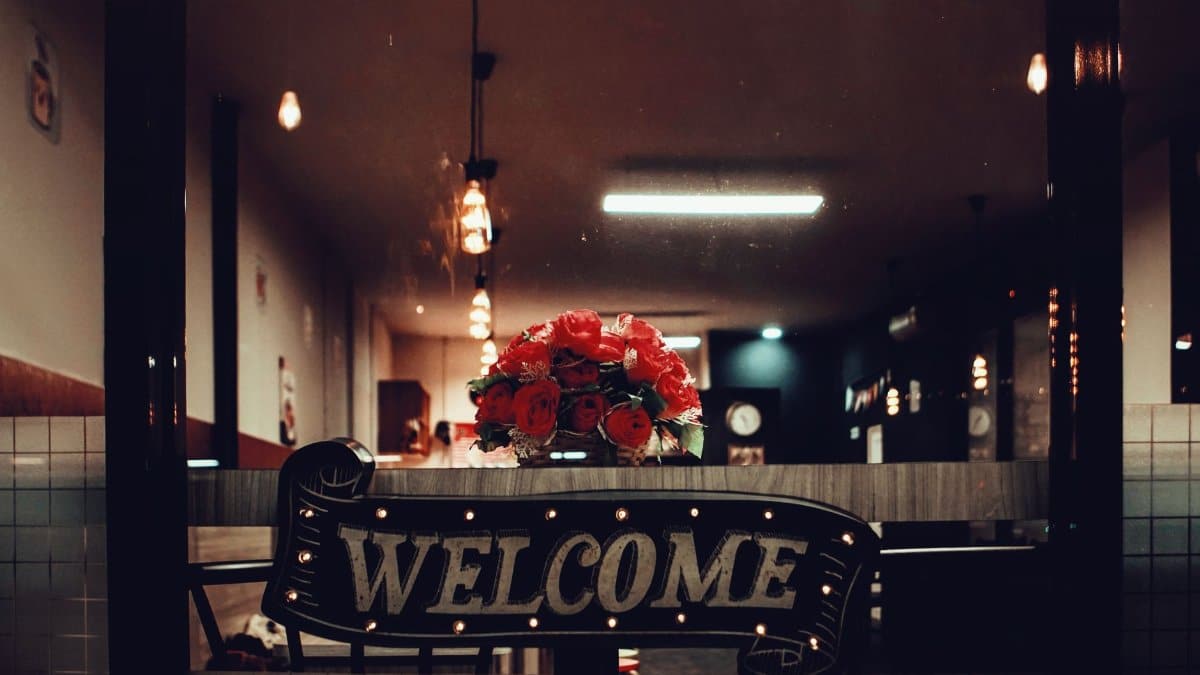 Warm and inviting restaurant interior with a welcoming sign and flower bouquet.