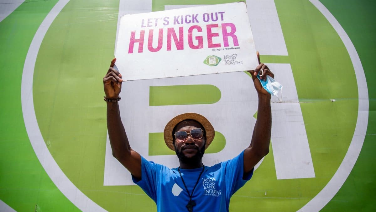 Man holding a sign promoting a hunger awareness campaign at an outdoor event.