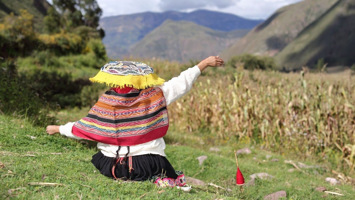 A person dressed in vibrant Quechua clothing enjoys the scenic Peruvian mountains, showcasing cultural heritage.