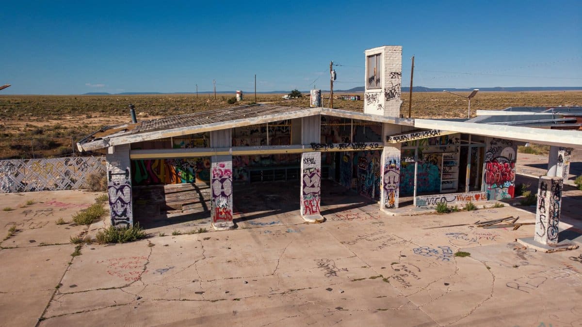 Aerial view of an abandoned, graffiti-covered building in the Arizona desert under clear blue skies.