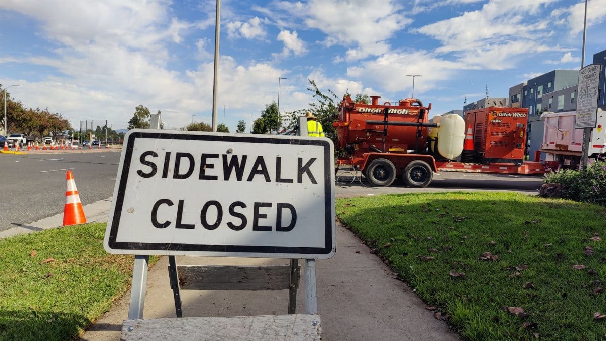 A sidewalk closed sign on an urban street highlighting road work and maintenance.