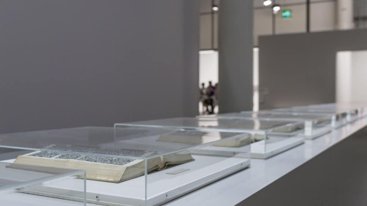 Modern art museum exhibit featuring open books in glass cases, highlighting contemporary interior design.