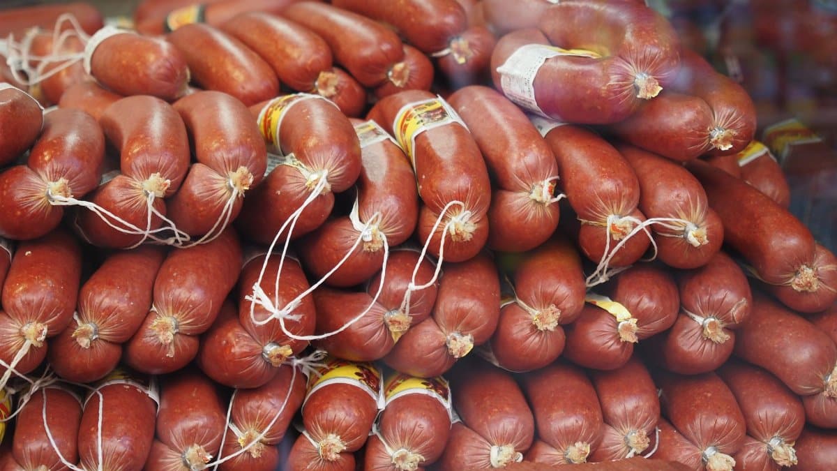 A stack of fresh sausages neatly arranged at a market, showcasing rich colors and textures of cured meats.