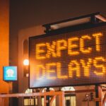 Mobile electronic traffic sign with inscription Expect delays placed on road in city street in evening time