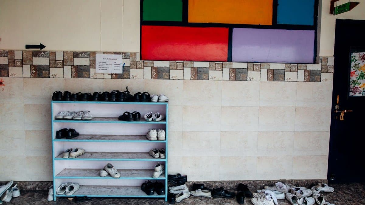 A school hallway with a colorful wall and neat shoe rack arrangement.