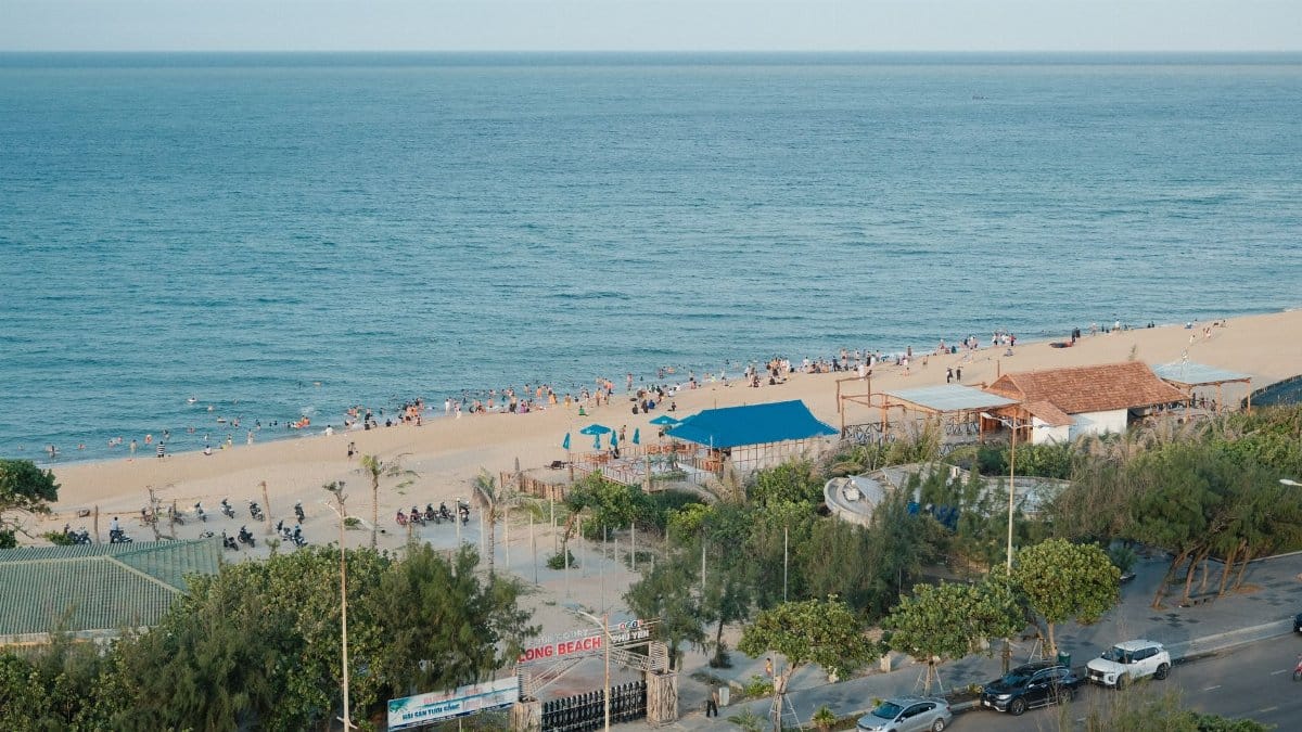 Aerial view of a vibrant sandy beach with visitors enjoying a sunny day by the sea.