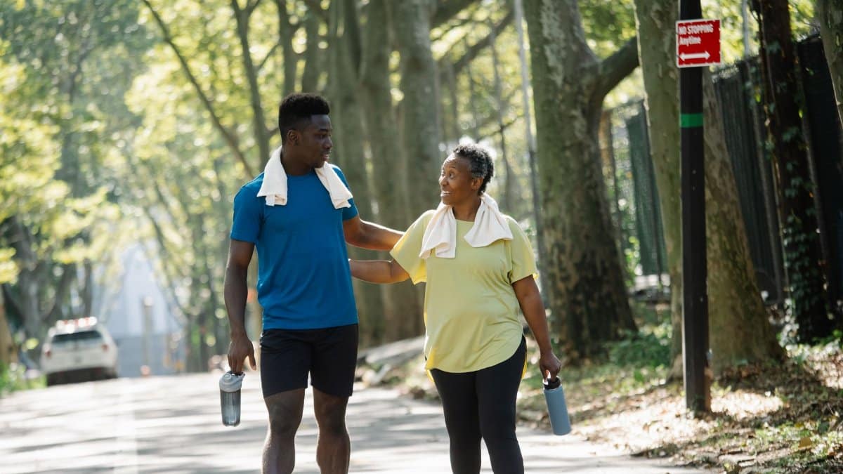 Two people jogging in a sunlit park, promoting fitness and well-being.