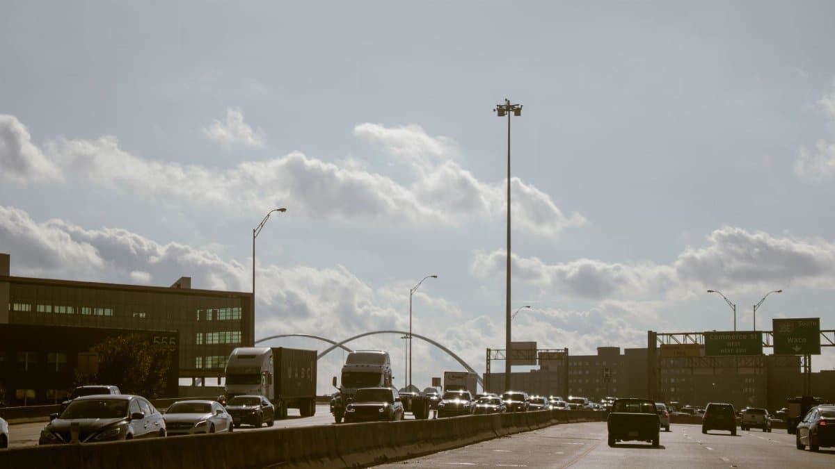 Traffic flows on a Dallas highway under a cloudy sky with visible city skyline. Perfect for urban lifestyle themes.