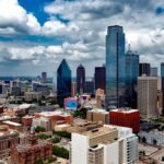 A stunning panoramic view of the Dallas skyline under dramatic clouds, capturing the city's iconic skyscrapers.