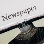 Close-up of a vintage typewriter printing the word 'Newspaper' on paper.