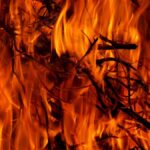 Close-up of a dynamic fire with vivid orange flames engulfing firewood, creating warmth and dramatic heat.