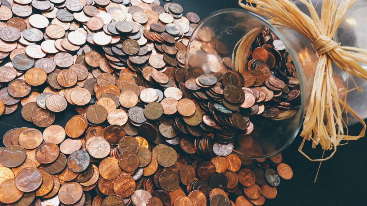 Spilled jar of pennies creating a pattern of coins representing savings and finance.