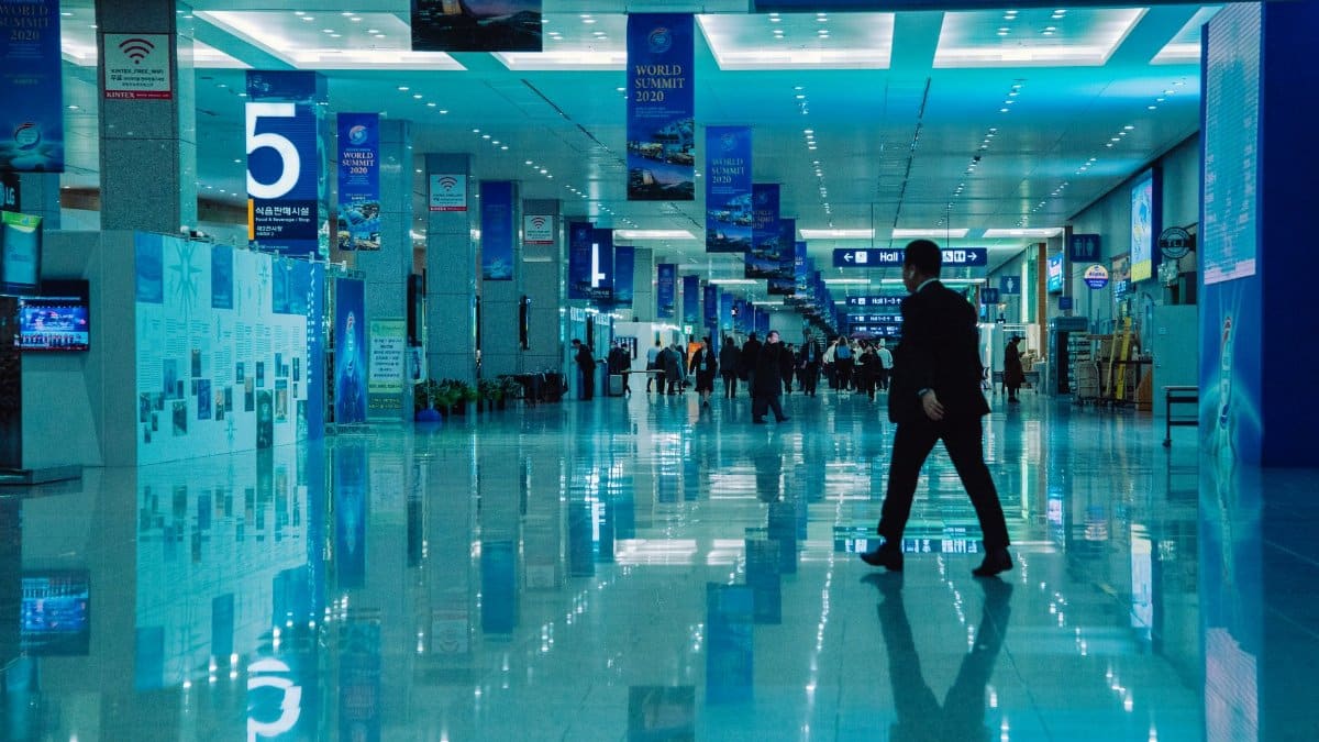 An indoor view of a busy conference hall during World Summit 2020 with directional signs and reflections.