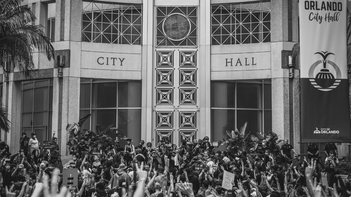 Monochrome image of protesters gathered at Orlando City Hall during a rally.