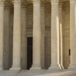 The Supreme Court of the United States with iconic marble columns and statue, captured in natural light.