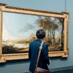 A man admires a large framed painting in an art gallery, England.