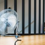 A sleek electric fan placed on a wooden floor in a modern indoor setting, providing comfort and cooling.