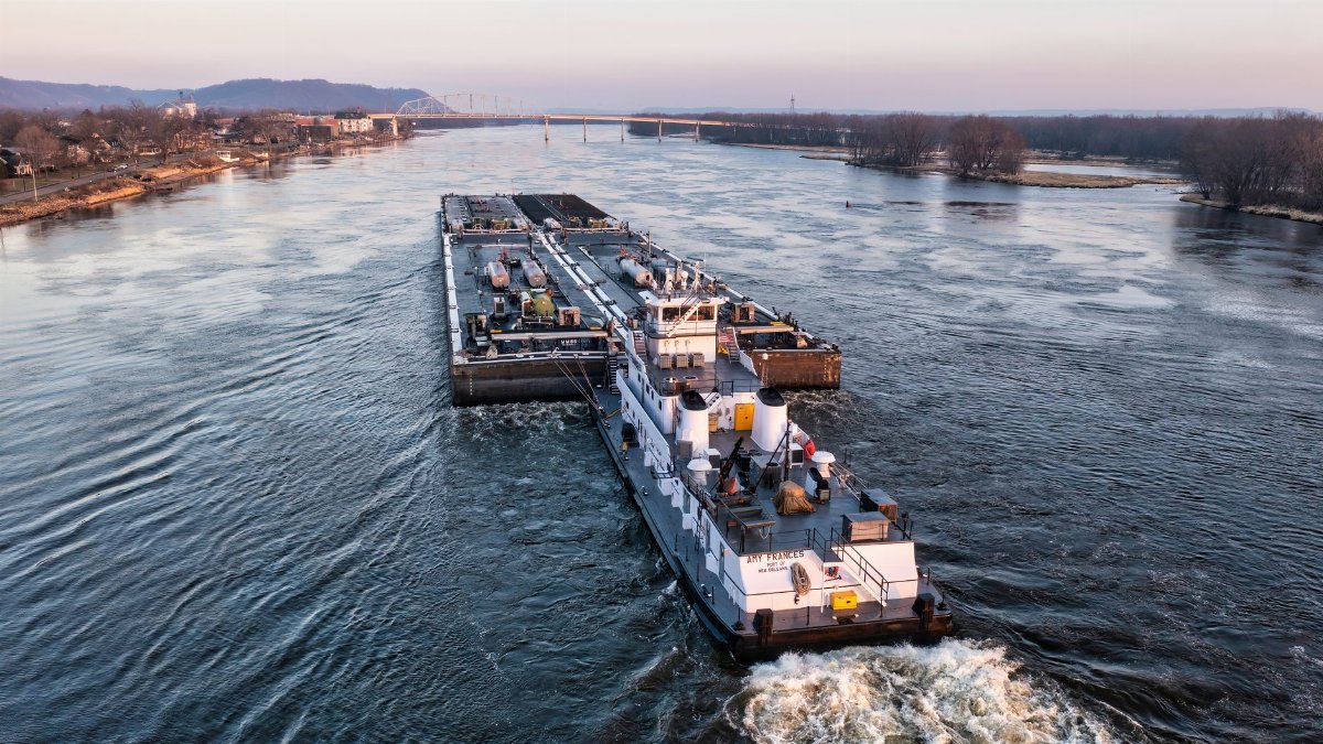 Aerial view of a cargo barge navigating the Mississippi River near Wabasha, Minnesota at sunset.