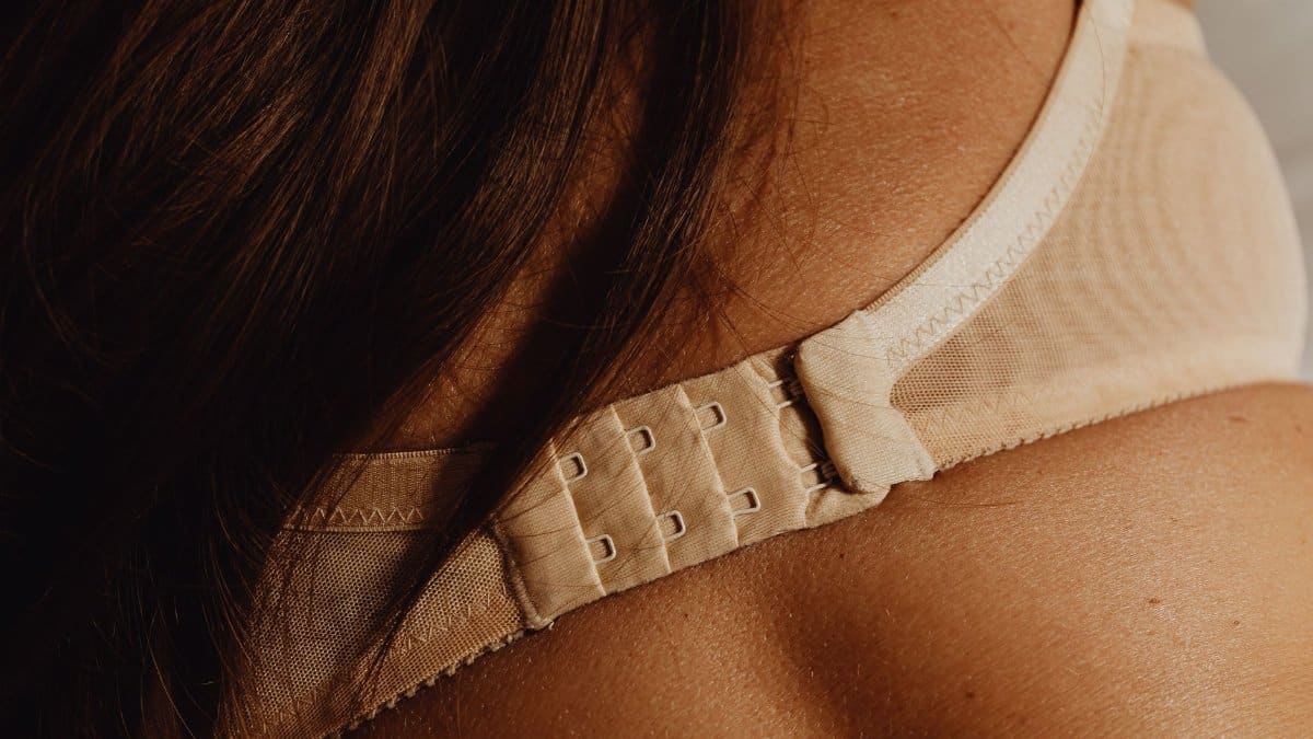 Intimate close-up of a beige bra clasp on skin, highlighting details and texture.