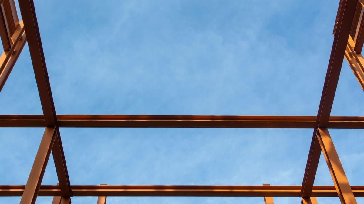 Silhouette of a metal framework against a bright blue sky, captured from below.