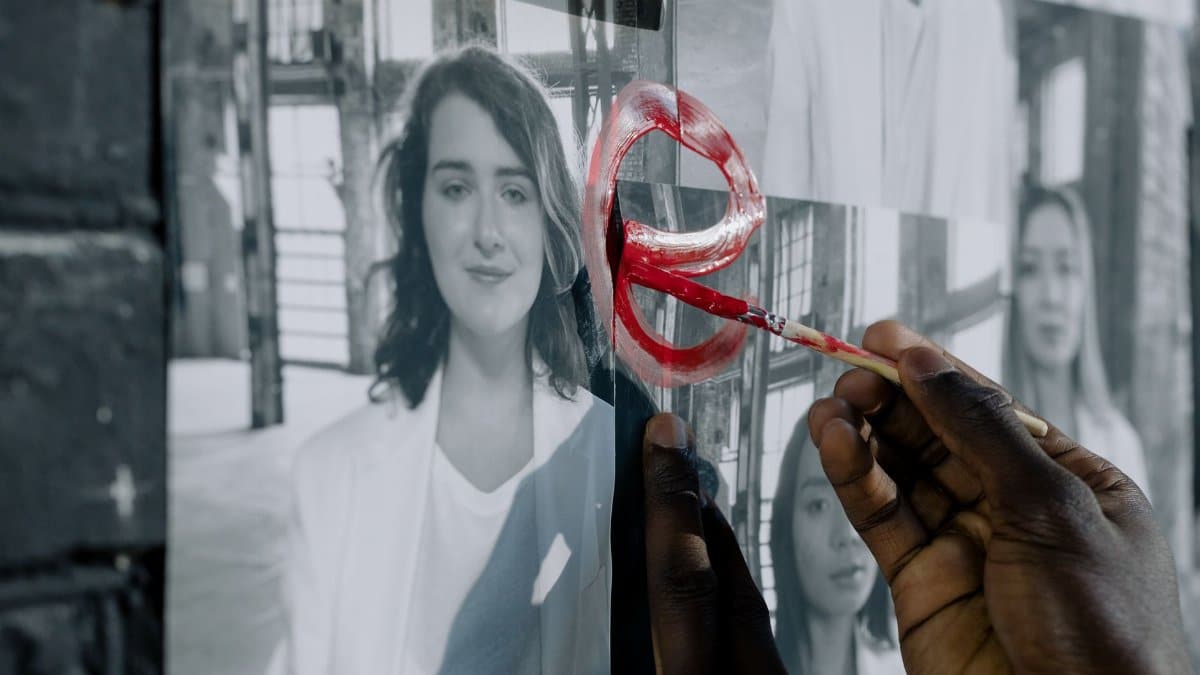 A hand painting red symbols on black and white photos, emphasizing artistic expression.
