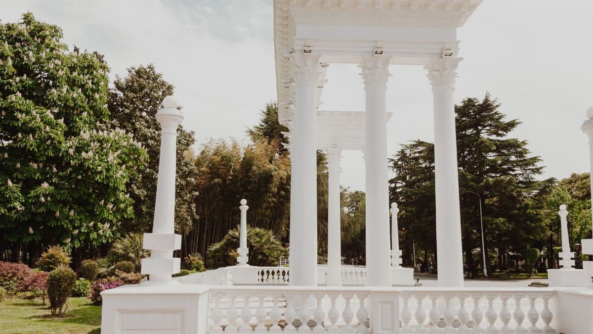 Majestic white columns in a lush green park enhance architectural elegance.
