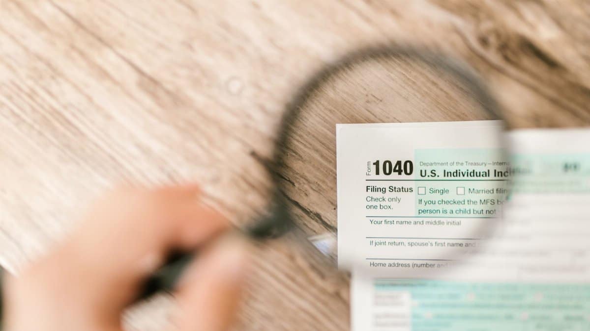Close-up image of IRS Form 1040 under a magnifying glass on a wooden surface.