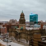 Aerial view of Detroit city showcasing historic and modern buildings under a cloudy sky.