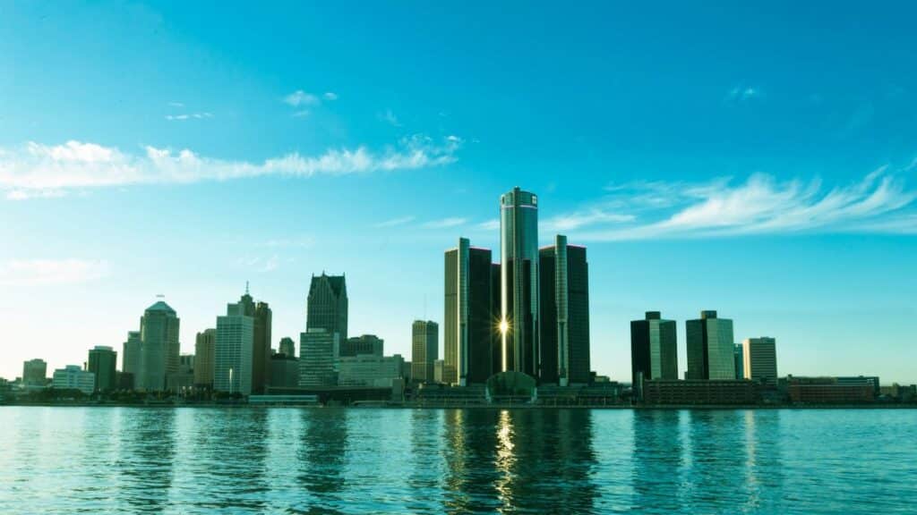 A beautiful view of the Detroit skyline reflecting on the river at sunrise, showcasing modern skyscrapers.